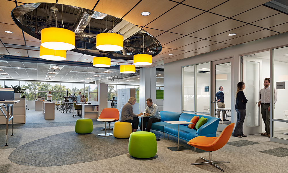 <p>The bright orange actuators can be viewed in intentionally carved out ceiling plenum vignettes throughout the three stories. Although the open office environment is not new to this company, it is achieved without the traditional tall panel systems. The low profile office furniture prevents isolation and allows for ease of communication, collaboration, and teaming. Although individual work areas are assigned, the workplace design strategy was to provide options and choices of work settings for team-based and heads down work. Huddle rooms, cafes, and soft seating areas invite staff to gather informally or focus on task. </p>
