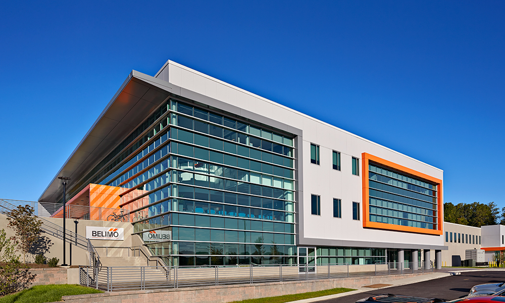 <p>The large scale of the building is moderated by first punctuating the long Manufacturing component with the three-story Office component. These components are further articulated with framed expanses of glass curtain wall. The balance of the facade takes a modular approach using precast concrete panels with a large repeating window.</p>
