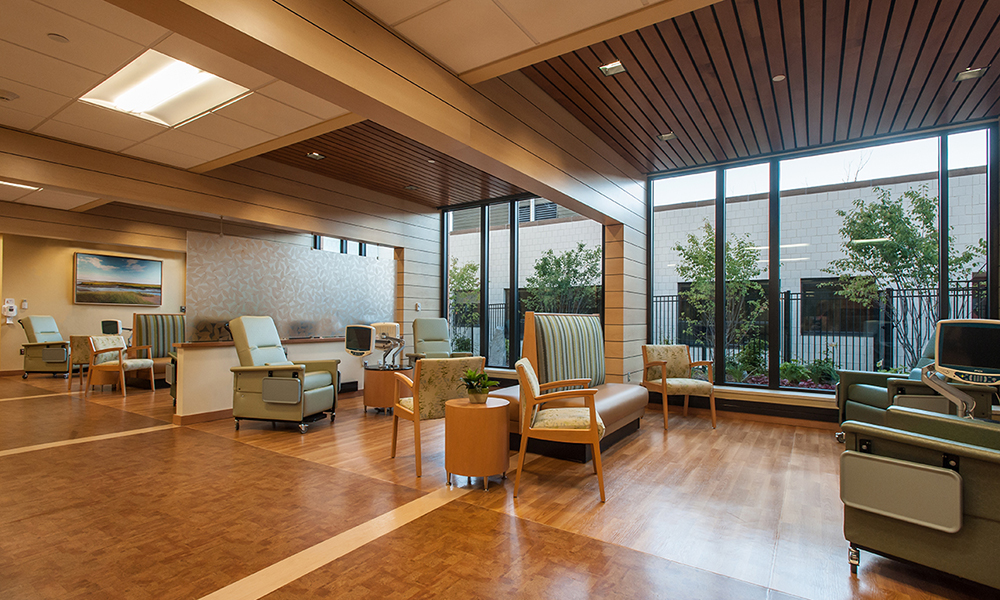 <p>Large wooden beams span across the ceiling of medical oncology, connecting infusion bays and nursing stations to the garden. The ceiling between the beams rises to meet the exterior windows, maximizing the natural light to the area. </p>
