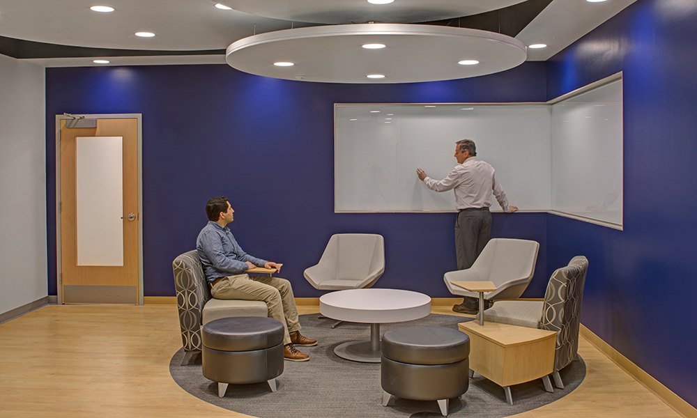 <p>This new workplace environment provides a variety of team spaces, both enclosed and open, with writeable back-painted glass wall surfaces and technologically advanced flat panel screens with videoconferencing capabilities encouraging group work.</p>
