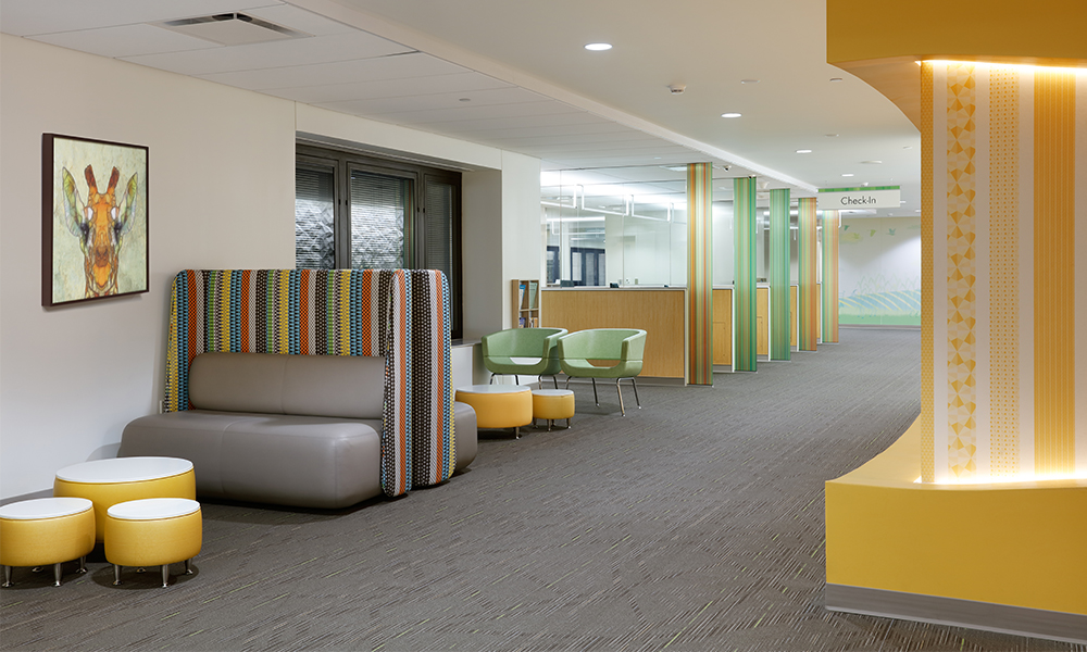 <p>The check-in area gives patients and families privacy with vertical glass dividers. Minimal waiting room seating is provided, aligning with the clinic’s operational model to quickly bring patients to exam rooms.</p>
